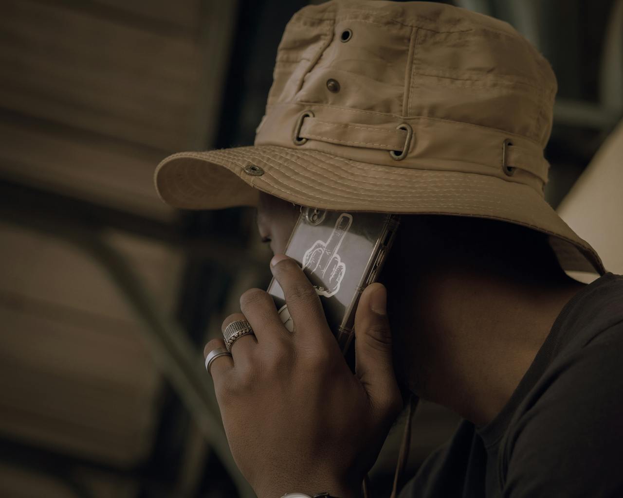 Close-up of a man wearing a hat talking on a cellphone with a unique case design.